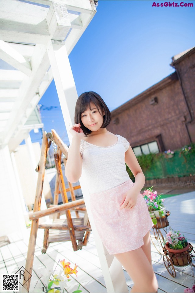 A woman in a white top and pink skirt posing for a picture.