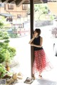 A woman leaning against a wooden pole in a courtyard.