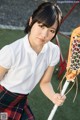 A young woman holding a lacrosse stick on a field.