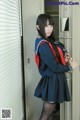 A woman in a school uniform standing in front of a locker.