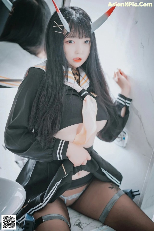 A woman in a black and white outfit sitting on a counter.