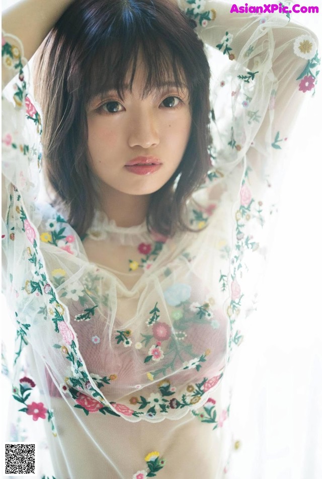 A woman in a sheer white dress with flowers on it.