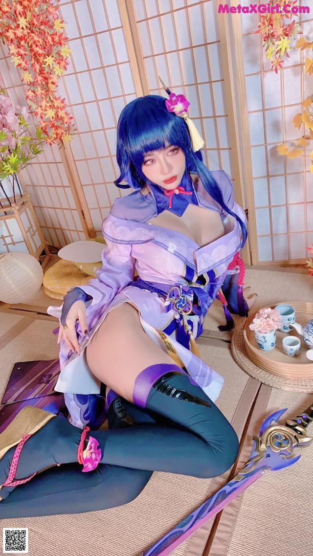 A woman in a purple and blue outfit sitting on the floor.