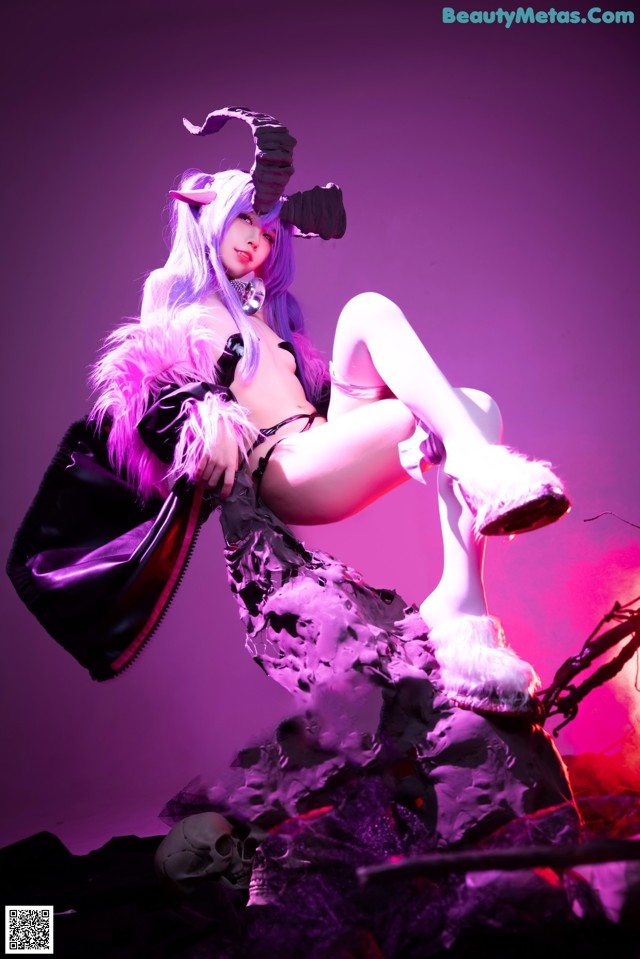 A woman dressed as a demon sitting on top of a rock.