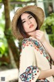 A woman wearing a straw hat is posing for a picture.