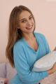 A woman in a blue shirt holding a pillow.