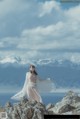 A woman standing on top of a mountain next to the ocean.