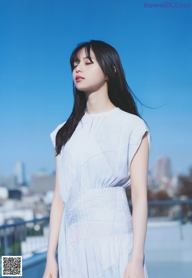 A woman in a white dress standing on a rooftop.
