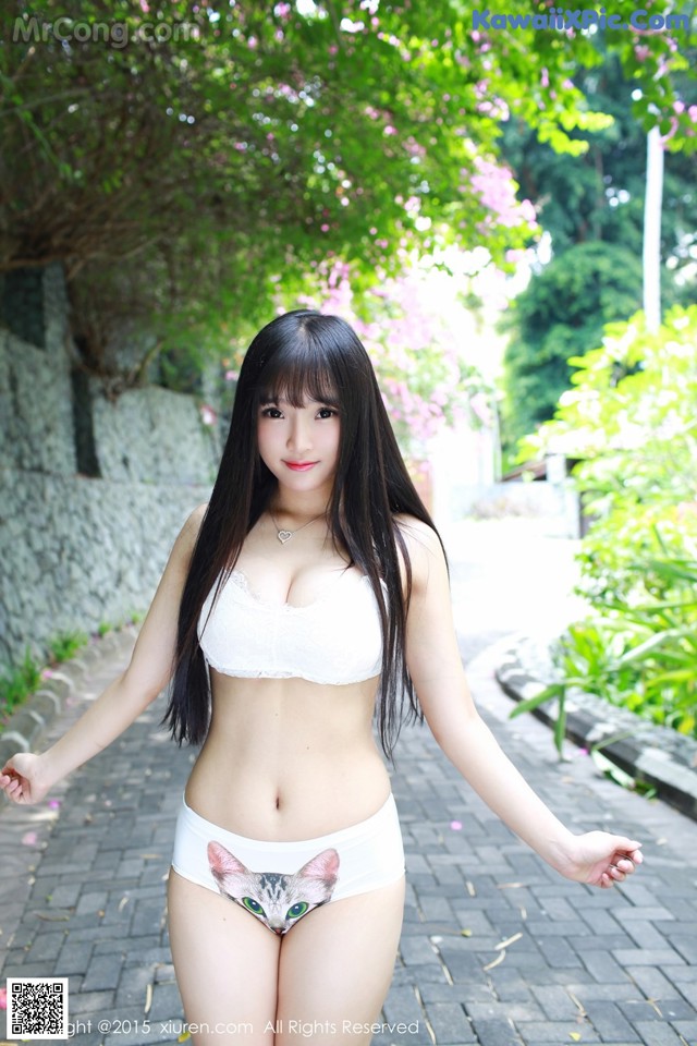 A woman in a white bikini with a cat on her underwear.