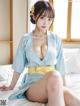 A woman in a blue kimono sitting on a bed.