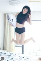 A woman jumping on a bed holding a pillow.